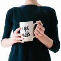 A woman holding a white mug reading “Like a boss,” photo by Brooke Lark