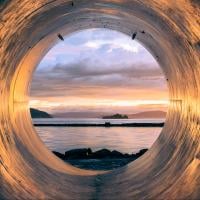 Sunset over the sea seen from the inside of a large pipe, photo by Erlend Ekseth