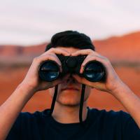 Photo of a person looking through binoculars, by Evan Kirby