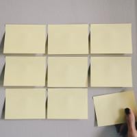 Person adding a square to a grid of sticky notes, photo by Kelly Sikkema