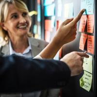 Project manager smiles while pointing to action items on sticky notes
