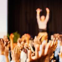 People raising their hands at a conference