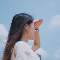 Woman with her hand over her eyes looking into the distance