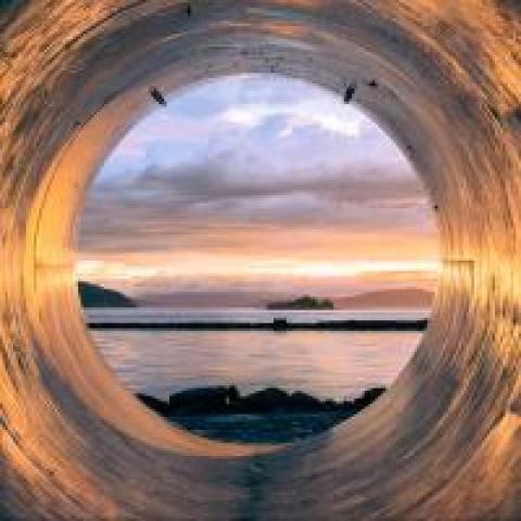 Sunset over the sea seen from the inside of a large pipe, photo by Erlend Ekseth
