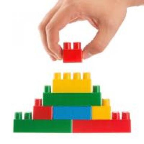 Hand putting together units of Legos