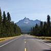 A two-lane road heading toward a mountain, photo by Jamison McAndie