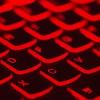 A computer keyboard lit up red, photo by Taskin Ashiq