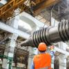 Man guiding heavy equipment in a manufacturing plant