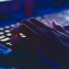 Hacker typing on a backlit computer keyboard