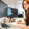 Software engineer looking at her computer monitors and integrating code